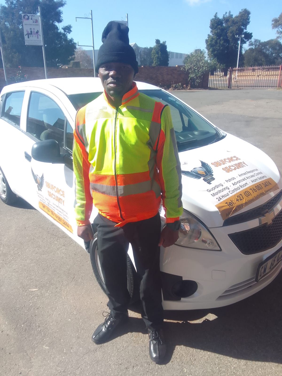 SbuForce Security guard standing beside a marked patrol vehicle